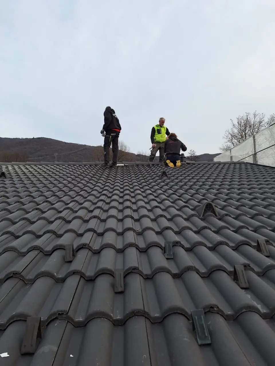 Team working on the ridge of a tiled roof